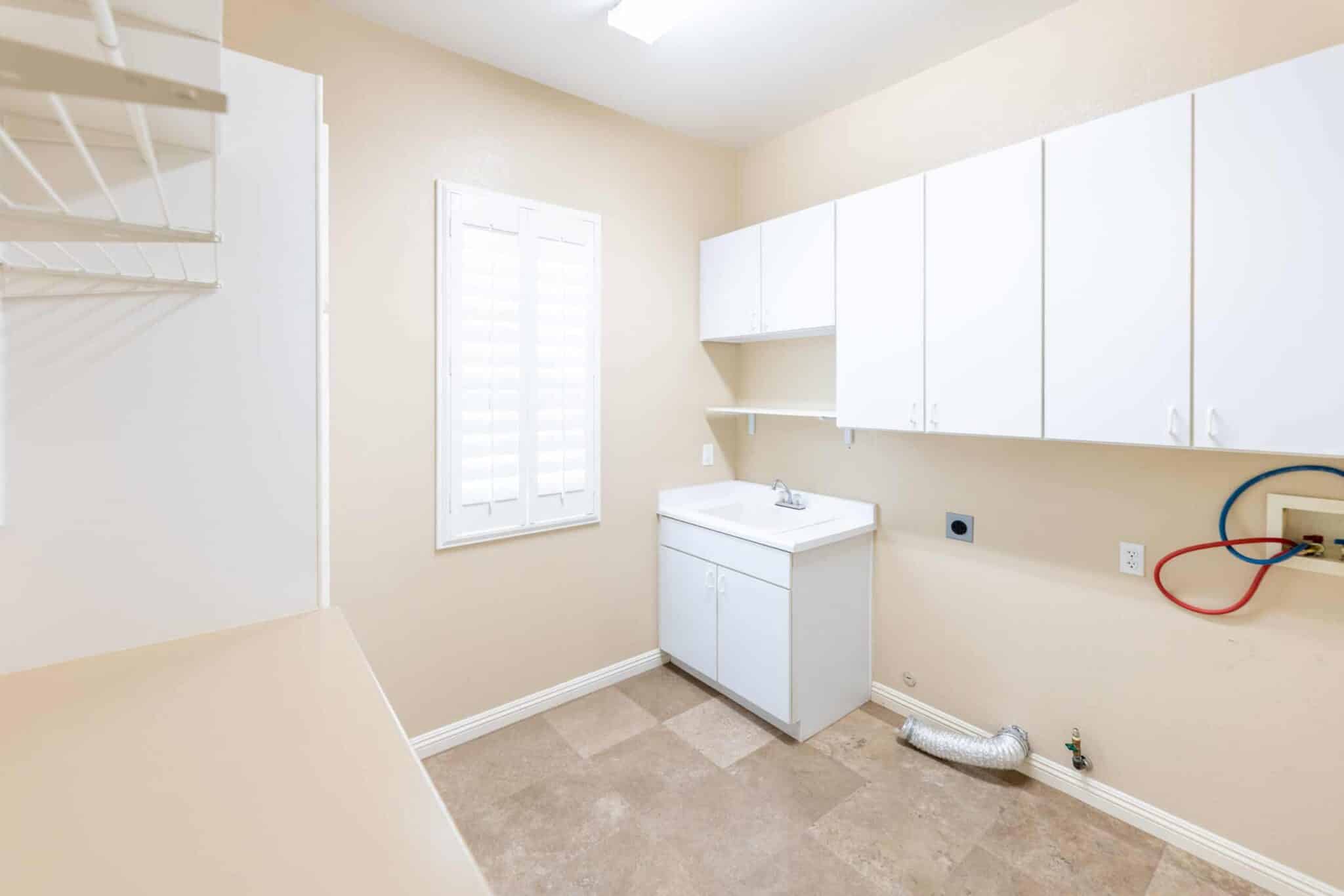 The downstairs laundry room with abundant cabinets, a closet, and utility sink.